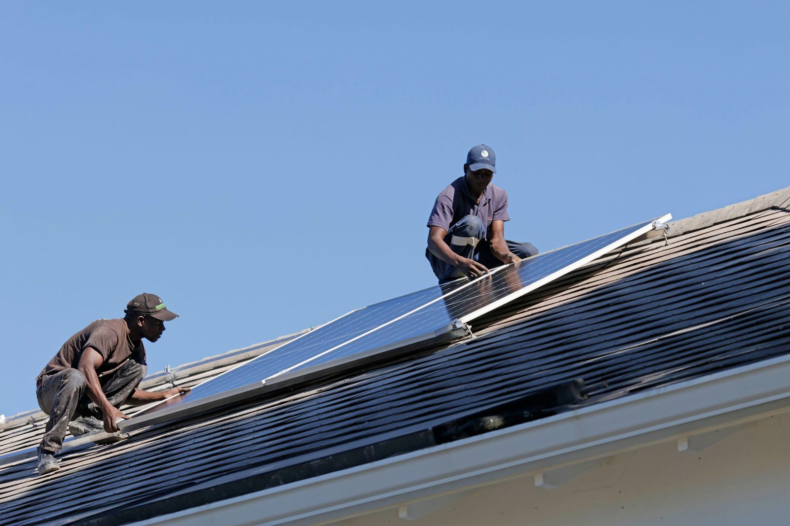 Two installers fitting solar panels on a roof, Goiás, Brazil