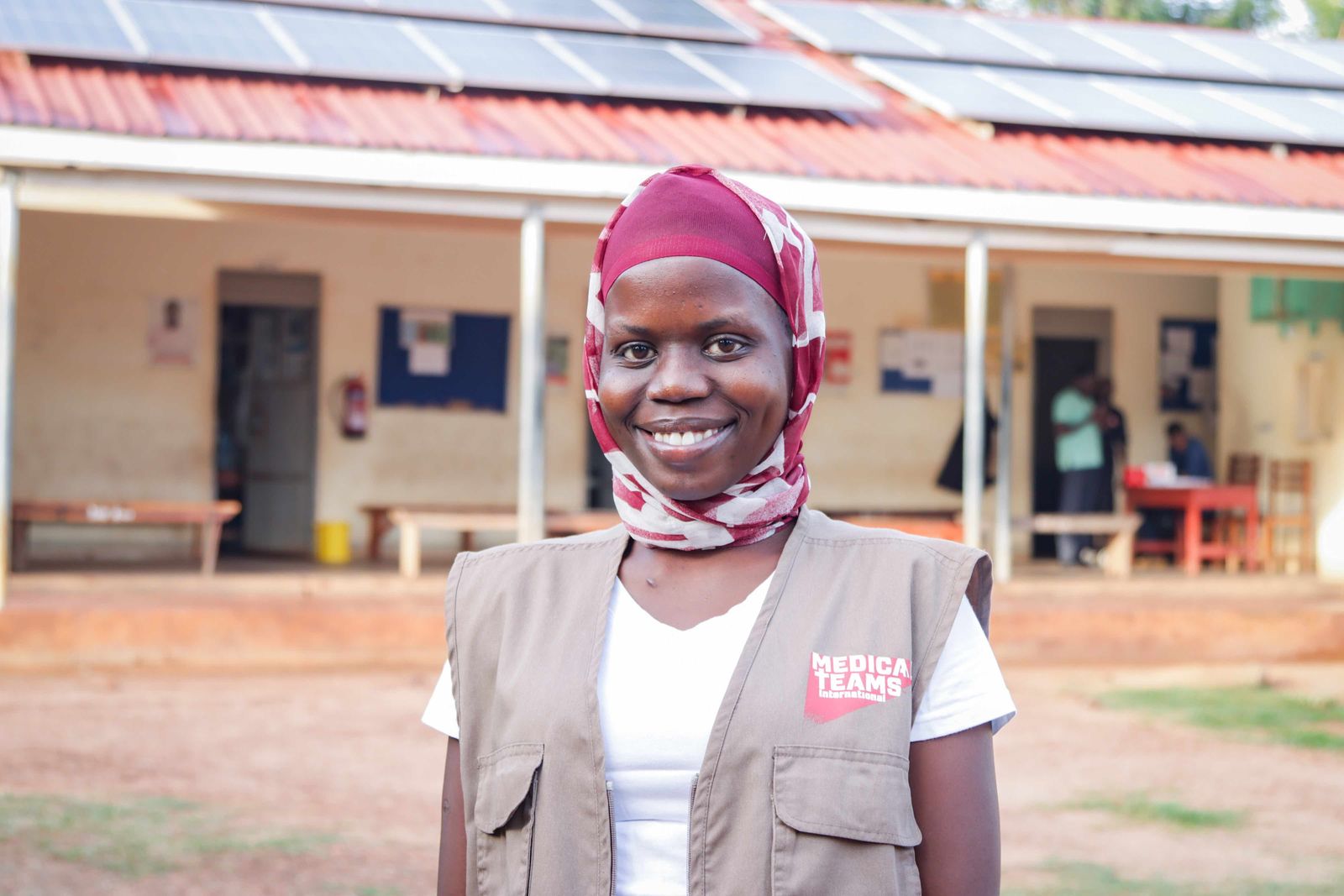 Health worker in front of a clinic with rooftop solar, Uganda